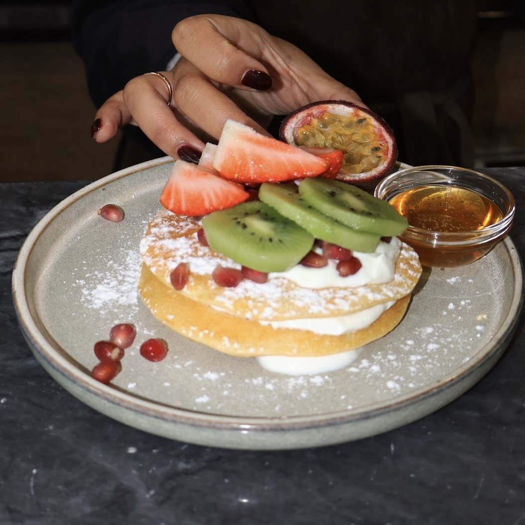 Three homemade pancakes, Greek yogurt, passion fruit, kiwi, strawberry, honey, powdered sugar